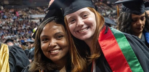 Two smiling students celebrating at Commencement