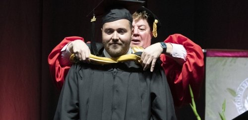 MSW student being hooded at Advanced Degree Commencement