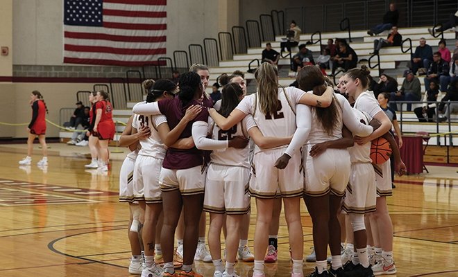 Women's basketball team in a group huddle on the court