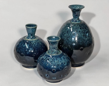 Photograph of three green-blue ceramic vases with intricate glaze designs