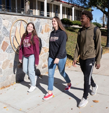 Three students walking together on the quad in fall