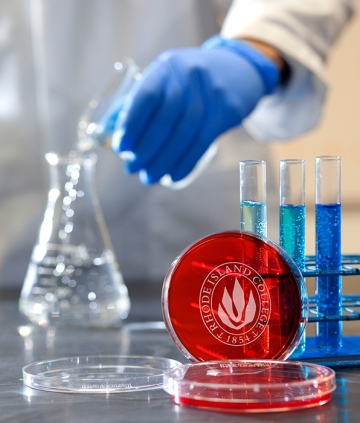 Liquid being poured into beaker, with RIC petri dish nearby