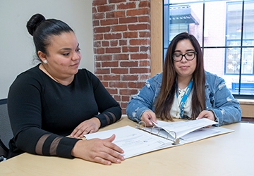 Students collaborating at a table, sitting over a binder