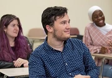 Students smiling, engaged while at desks in classroom listening