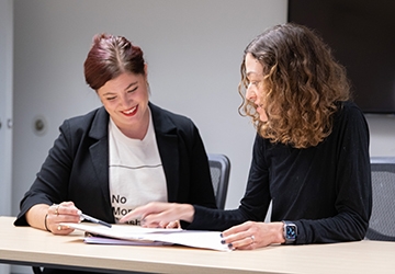 Two people looking at papers, working together at a table