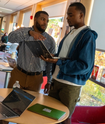 People standing, holding laptop, talking together about what's on the screen