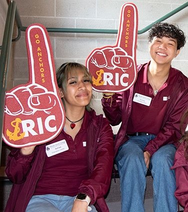 Two orientation leaders smiling, with RIC foam fingers