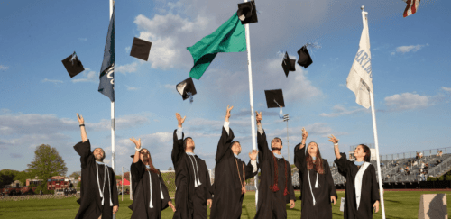seven graduates throwing their caps after graduating