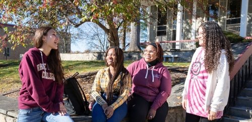 Four students talking outside the library in the fall