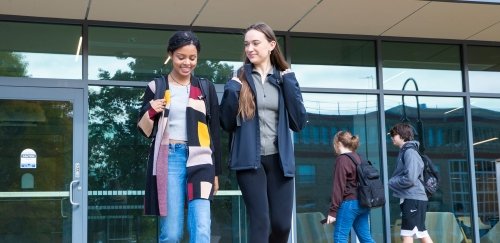 Two students walking outside Gaige Hall