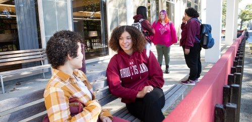 Students sitting and standing in front of Adams library