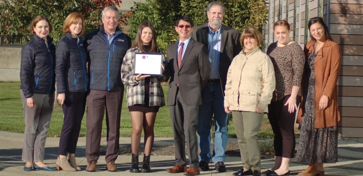 A group of people presents a student with a certificate for her scholarship