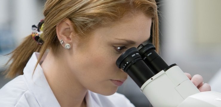 Student peering into the lens of a microscope